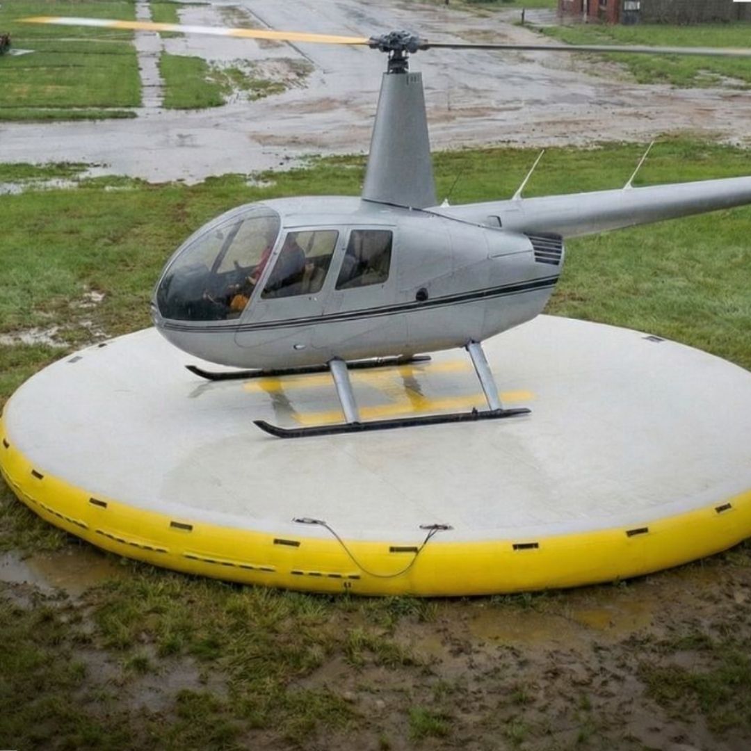 Hardline Helipad deployed on wet, muddy, and grassy terrain, providing a clean, stable white and yellow landing platform
